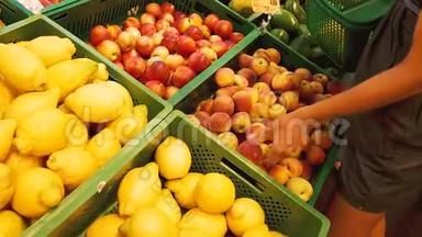 女人的手在超市里摘桃子。 女人从超市的盒子里拿水果